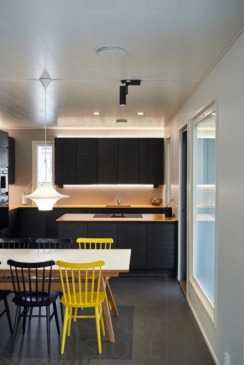 Directional, black led rail light illuminating a dining area. Led strips illuminating the kitchen with indirect light. Ledstore.fi